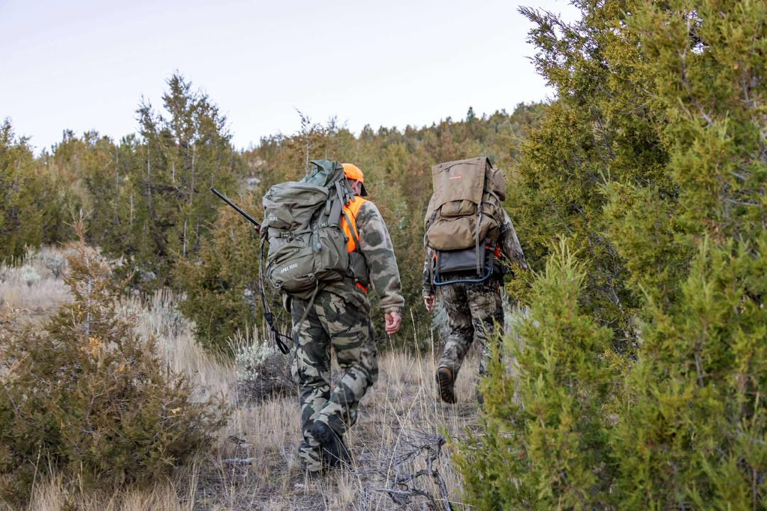 Backcountry hunter carrying heavy load with SIATREX expedition hunting gear system in rugged terrain